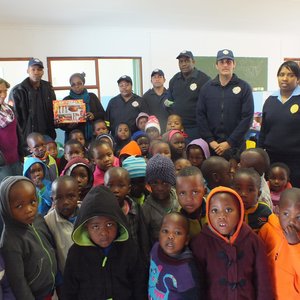 Links agter oorhandig Thembelani Xovula die Brandweerprys van Selina Nqejane (5) van Masakhane CrÃ©che aan Gloria Silku, wat dit namens Selina in ontvangs geneem het